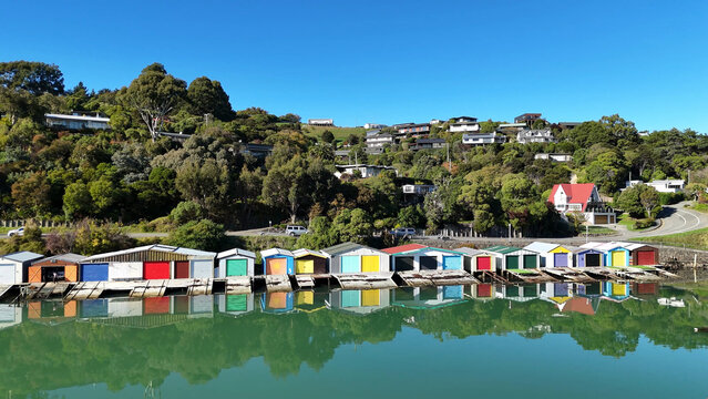 Colorful Boathouses Reflecting in Calm Water at Akaroa Bay New Zealand