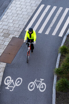 Overhead view of cyclist on bicycle in bike line crossing pavement crosswalk in Stockholm Sweden showing commuting transport and urban motion