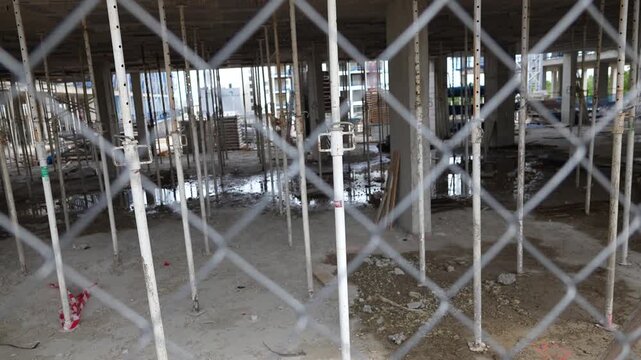 Madrid, Spain - May 4, 2026: Interior view of a building under construction with concrete floors and adjustable steel support columns seen through a chain link fence in Madrid, Spain.