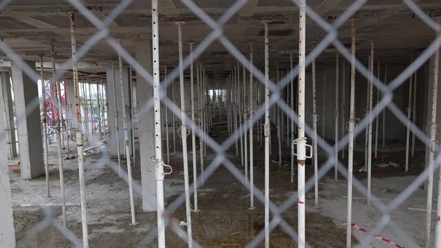 Madrid, Spain - May 4, 2026: Interior view of a modern building under construction showing concrete floors and temporary support columns behind a chain link fence in Madrid, Spain.
