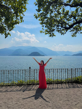 lake como embrace; happy woman in red dress near gate