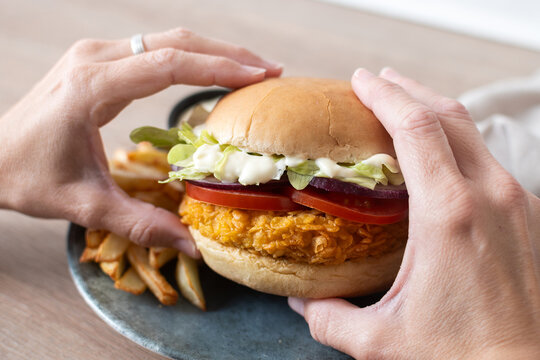 Woman holding crispy chicken burger ready to eat. Close up
