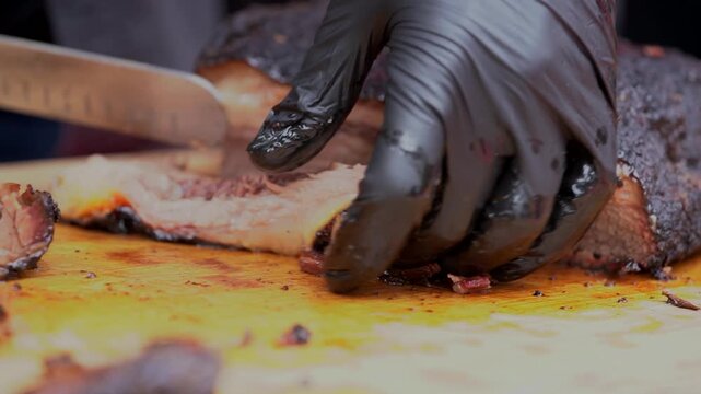 A person wearing black gloves prepares food on a cutting board
