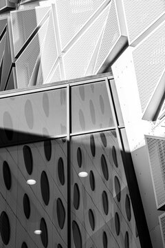 Monochrome modern architecture facade building glass reflection windows with abstract pattern geometry featuring perforated panels strong contrast and shadows