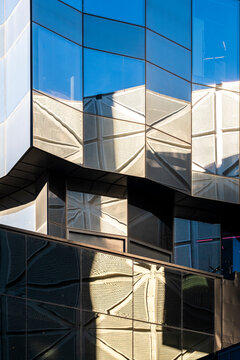 Angular modern architecture facade building glass reflection windows at a sharp corner creating abstract pattern geometry with faceted structure and glare