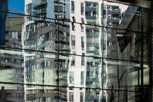 Layered modern architecture facade building glass reflection windows creating abstract pattern geometry with green tinted mirrored surfaces and distortion