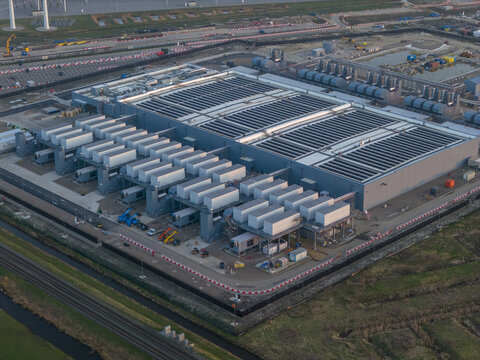 Aerial view of the Google data center with extensive cooling systems, industrial infrastructure and wind turbines in the distance.