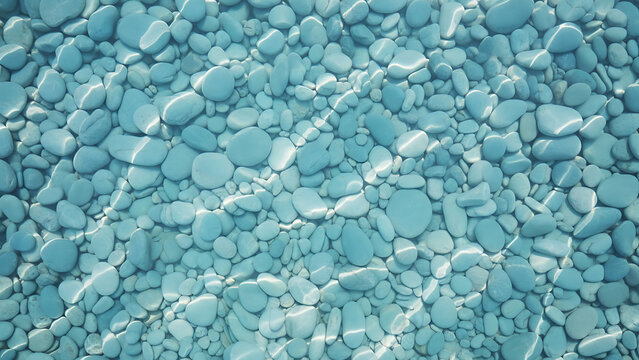 Clear blue water covering smooth pebbles on sea floor. Sun rays shining through transparent ripples on beach stones. Natural summer background for vacation and marine texture design.