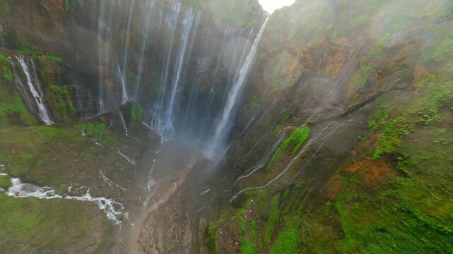 Cinematic FPV drone dive into Tumpak Sewu waterfall in East Java, Indonesia. Dynamic flythrough over jungle cliffs and powerful cascading water with immersive motion and speed.