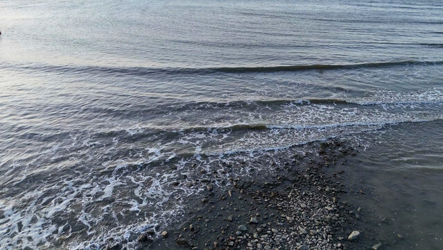 Aerial View of Gentle Ocean Waves Washing Over a Rocky Shoreline