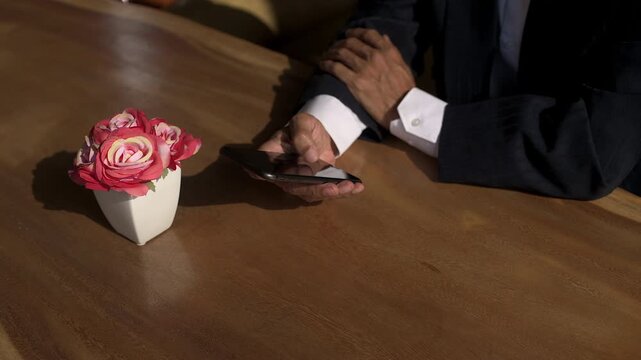 High angle front shot view of Asian business man hand typing messages on smartphone indicating busy communications