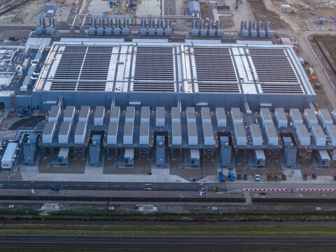 Aerial view of a Google data center industrial complex featuring massive cooling infrastructure and ventilation systems with construction equipment on the ground.