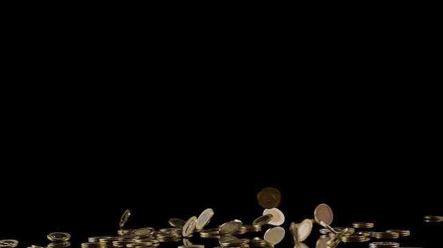 Saudi coins falling in slow motion against a black background, representing wealth and finance.