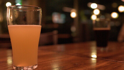 Cold Glass of Hazy Pale Ale on a Wooden Pub Table © blueringmedia