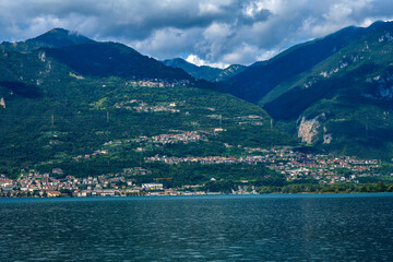Fototapeta premium Blick über den Iseosee auf die gestaffelte Hangsiedlung von Castro vor den Bergamasker Alpen, Italien
