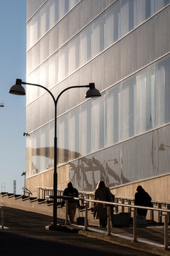 Evening commute in Stockholm as people pedestrians turn into silhouettes within modern urban architecture while shadows pull the group forward