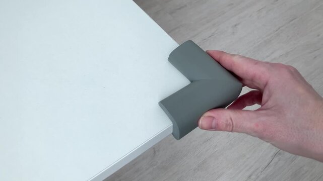 A woman's hand places a soft silicone corner. Safety silicone pads on the corner, protecting the child from injury,protects bumping child's head. Parents' concern for the safety of the baby