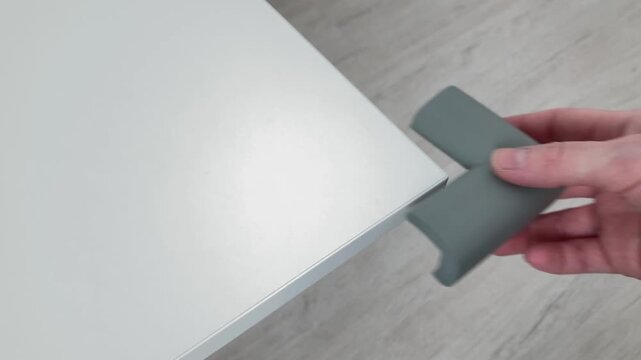 A woman's hand removes the soft silicone corner. Preventing bumps and injuries in a child. The desire of parents to protect the kid from possible household risks