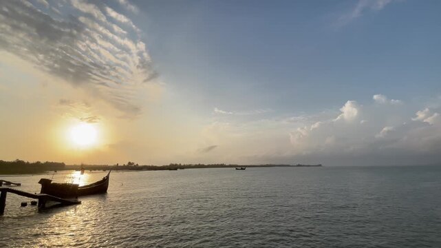 Traditional Wooden Vessel Sailing on Calm Sea Waves During Vibrant Tropical Sunset at cox's bazar in Bay of Bengal.