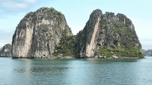 Limestone karst islands rising from calm waters in Halong Bay Vietnam, iconic travel landmark, nature landscape