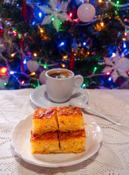 Greek orange pie and coffee on a handmade knitted tablecloth on the background of a Christmas tree in Greece