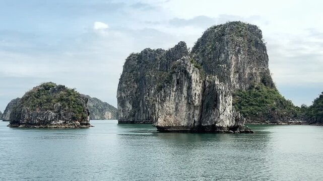 scenic limestone karst formations rising from tranquil waters in ha long bay vietnam, tropical travel scenery