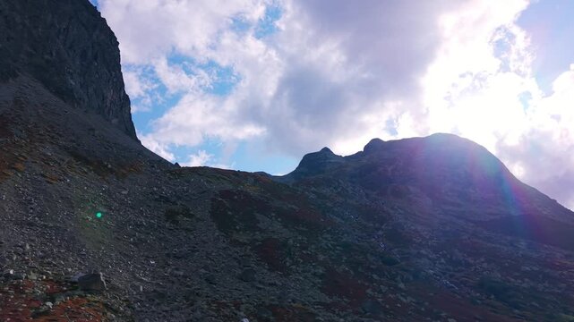 Sun rays breaking through clouds over rugged mountain peak in Swiss Alps at Julier Pass