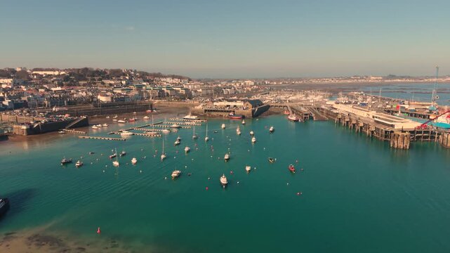 St Peter Port Harbour Guernsey.High reveal of the harbour from ferry berth and docks to model yacht pond with Belle Greve Bay and QEII Marina in the background and ship in port in late afternoon sun