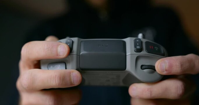 Close-up of drone pilot's hands operating joysticks and buttons of modern DJI remote controller