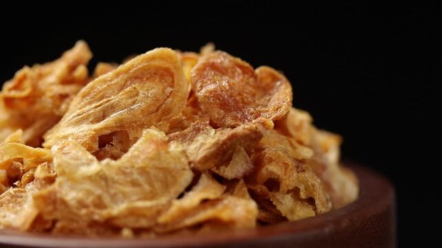 crispy fried shallots in bowl rotating on a black background, crunchy Thai food topping