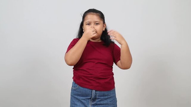 Asian little girl checking his odor underarm, close his nose with hand, feel disgusted the body strong smell, Unpleasant body odor, smell nasty reaction.