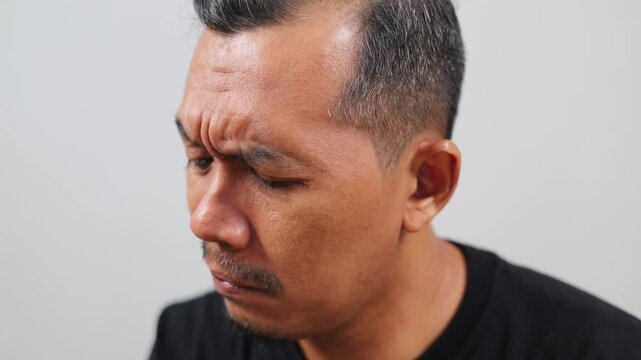 Funny Asian man is picking his nose using finger, close up