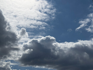 Naklejka premium Dramatic clouds fill a blue sky. Bright and dark cloud layers create a strong weather scene. Natural background for design and copy space..