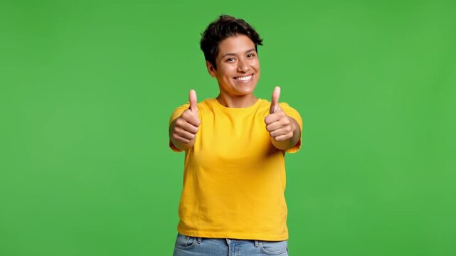 Smiling person in yellow shirt gesturing double thumbs up on green screen chroma key with cinematic steady cam for customer satisfaction marketing