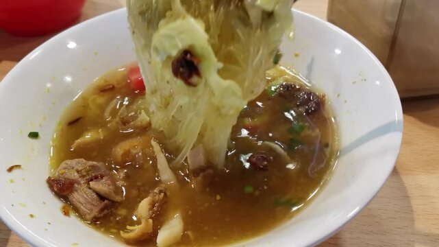 A delicious bowl of Soto Ayam (Chicken Soup) with chicken and rice noodles