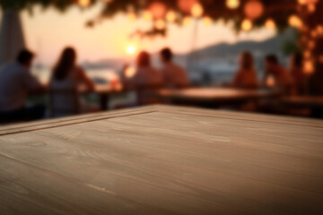 Fototapeta premium Empty wooden table with clean copy space for product placement in the foreground. Blurred background with people sitting in beach outdoor bar by the sea during warm sunset. Golden light.