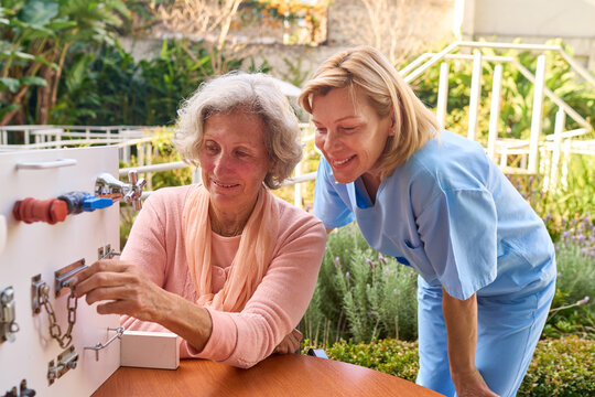 Senior Woman Doing Fine Motor Skills Exercises With Physiotherapist Outdoors In Rehab Center For Recovery And Rehabilitation After Injury