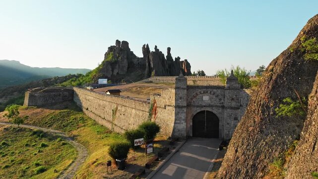 Belogradchik Fortress red rocks aerial view sunrise Bulgaria. Historic fortification balkan mountains scenic landscape morning drone travel tourism exploration destination.
