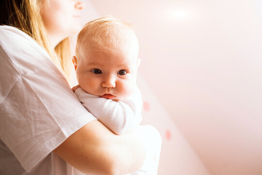 Portrait of a newborn baby. Mother holds a child in her arms. The first year of life. Care and health.