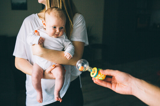 Portrait of a newborn baby. Mother holds a child in her arms. The first year of life. Care and health. ather gives a child a toy