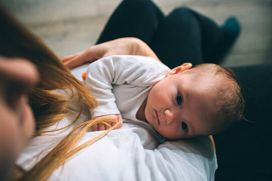 Portrait of a newborn baby. Mother holds a child in her arms. The first year of life. Care and care