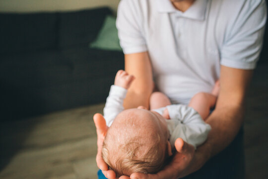 Portrait of a newborn baby. Father holds a child in her arms. The first year of life. Care and health