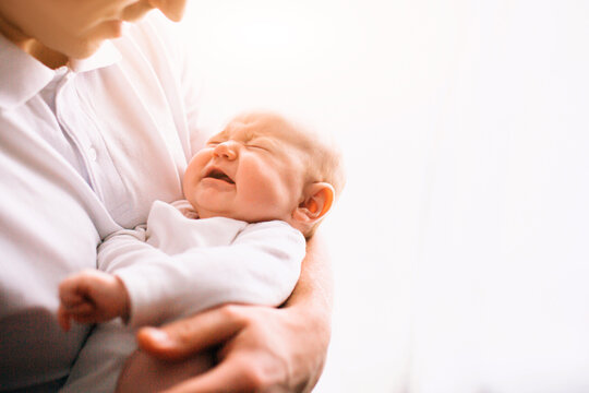 Portrait of a newborn baby. Father holds a child in her arms. The first year of life. Care and health
