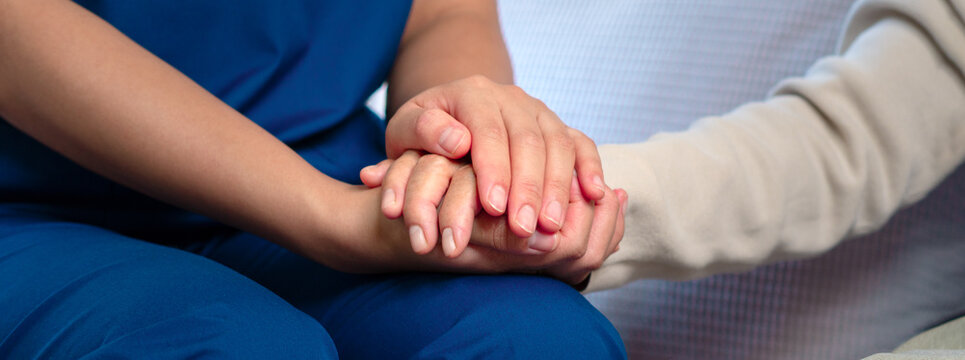Professional nurses provide attentive and empathetic care, holding the elderly person's hand while offering health advice.