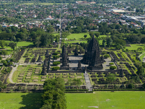 Aerial view of the Prambanan Temple complex featuring ancient stone spires and archaeological ruins surrounded by green lawns and trees in Prambanan, Daerah Istimewa Yogya, Indonesia.