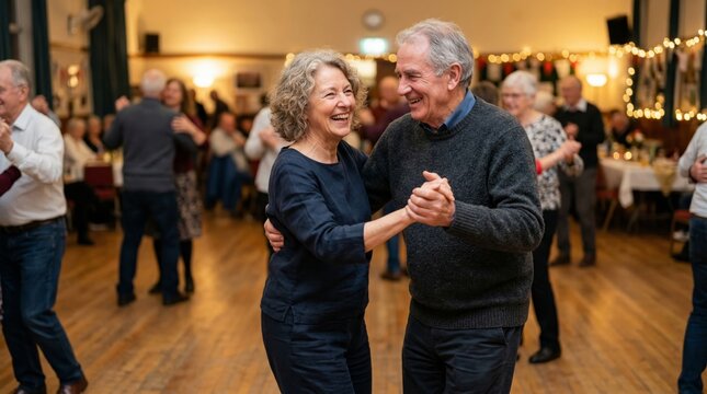 Senior woman and man dancing together at a lively community social event. Happy elderly couple enjoying a ballroom dance in a warm hall. Active retirement and healthy social lifestyle.
