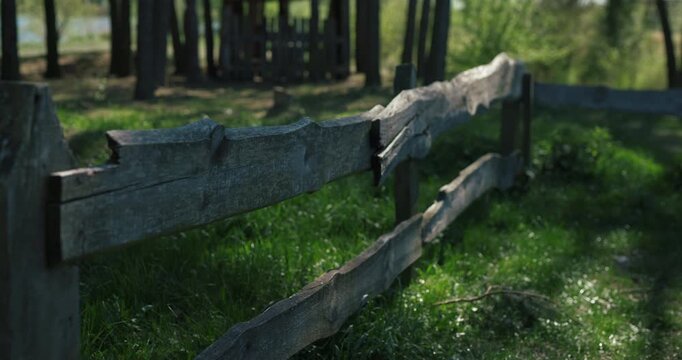 Close-up of a rustic timber fence with sunlit grass, audio included