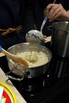 cocinero elaborando arroz cocido en un olla y echando caldo al guiso