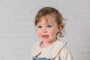 Naklejka premium portrait of a little girl with blond curly hair and blue eyes