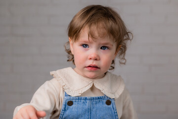 Naklejka premium portrait of a little girl with blond curly hair and blue eyes